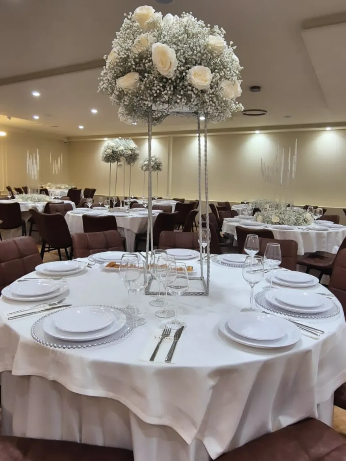 Gedekte ronde tafels met witte bloemen in de zaal